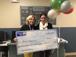 Two women with a large check at a homeless shelter