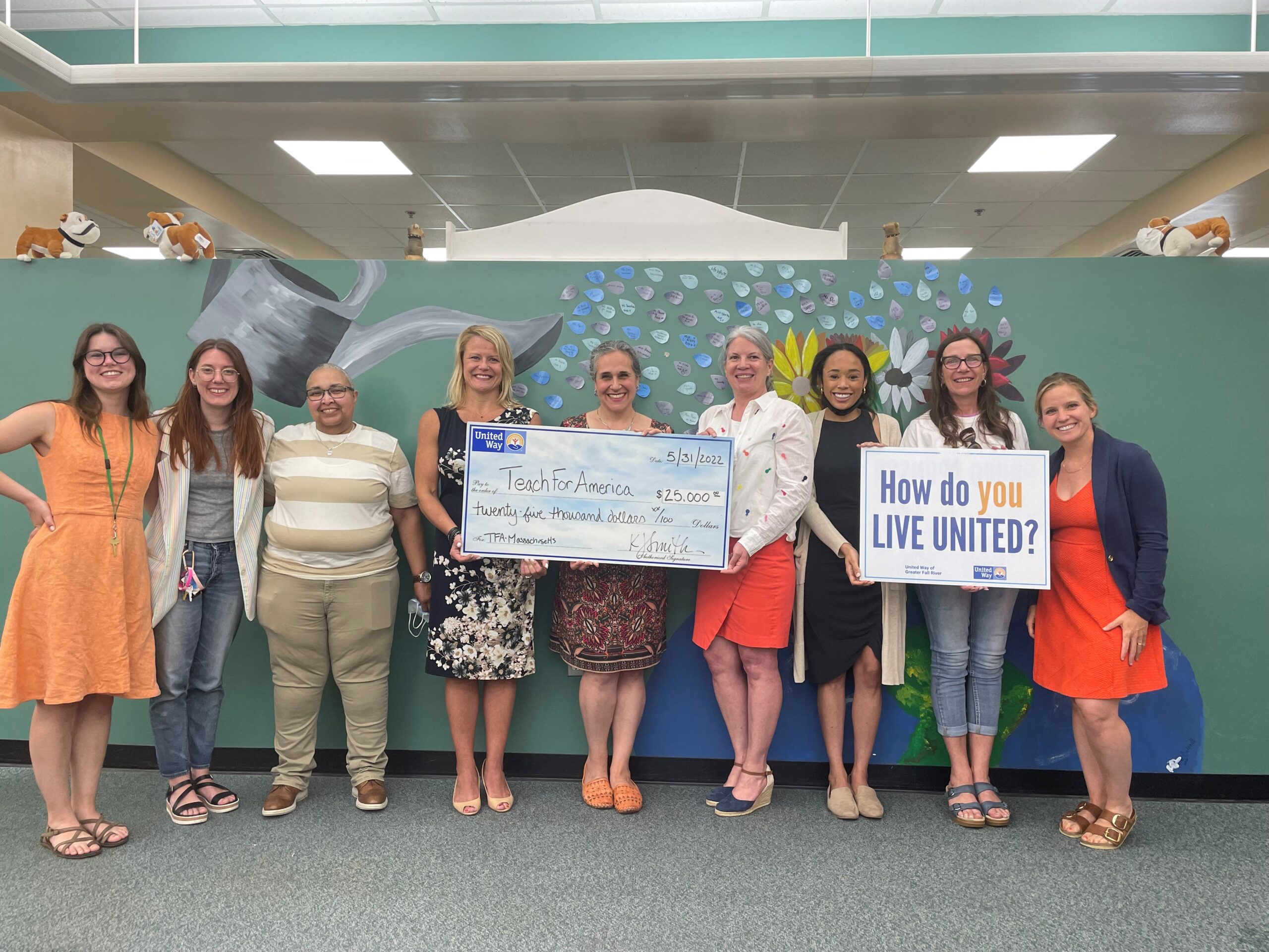 A group of female Teach for America representatives receive a check from women from United Way of Greater Fall River