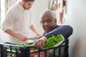Elderly man takes fresh produce out of basket
