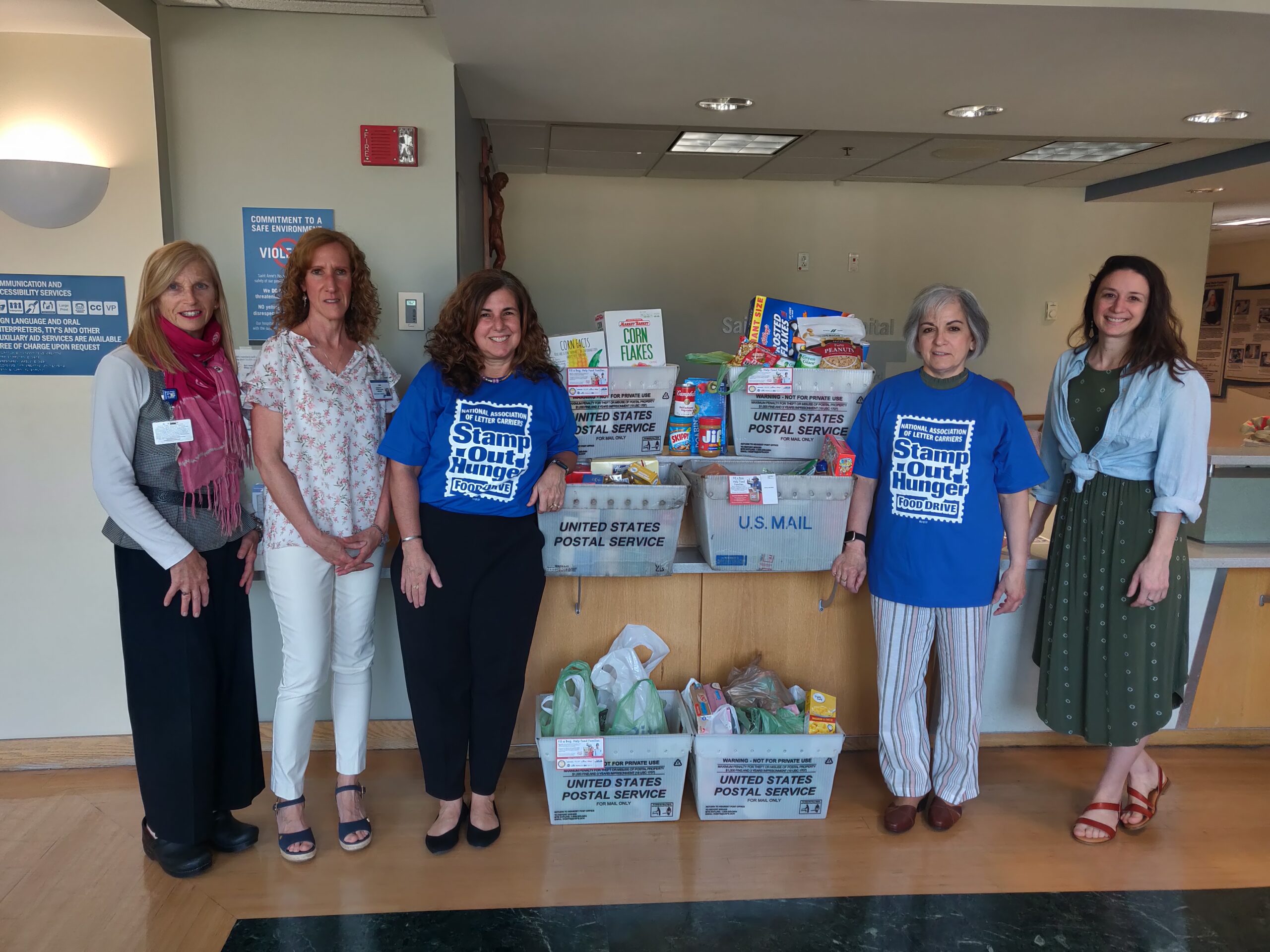 Saint Anne's Hospital employees pose with UWGFR employee next to donated food items in hospital lobby