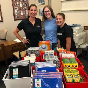 Volunteers posing behind school supply donations