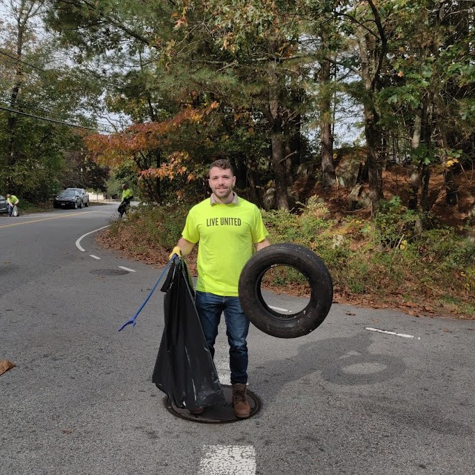 Clean-up volunteer holding trash bag and tire